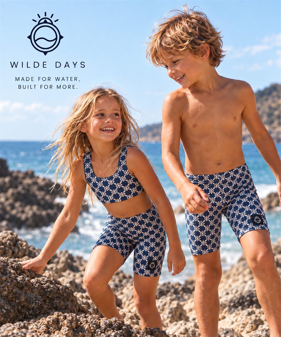 AI-generated visualisation: two children on rocks by the sea, wearing navy and cream turtle-print shorts and a matching crop top.